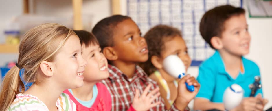 Fünf Kinder hören gespannt zu und lernen Musik